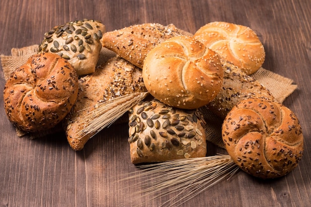 Auswahl an gebackenem Brot mit Samen auf einem Holztischhintergrund. Bäckerei. Ernährungssicherheitskonzept.