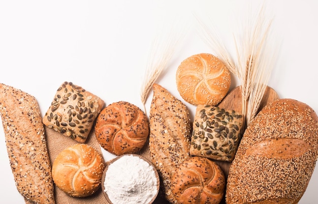 Auswahl an gebackenem Brot mit Samen auf einem weißen Tischhintergrund. Bäckerei. Ernährungssicherheitskonzept.