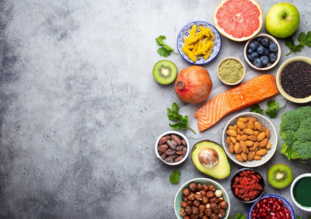 Foto auswahl an gesunden produkten und superfoods: lachs, obst, gemüse, beeren, goji, spirulina, matcha, quinoa, chia, nüsse mit kopierraum. sauberes essenskonzept, grauer hintergrund, draufsicht, nahaufnahme