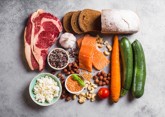 Auswahl an gesunder ausgewogener Lebensmittelzusammensetzung: Fleisch, Fisch, Gemüse, Brot, Getreide, Bohnen, Steinhintergrund. Rohe Zutaten zum Kochen gesunder Mahlzeiten, gut für die Ernährung, sauberes Esskonzept