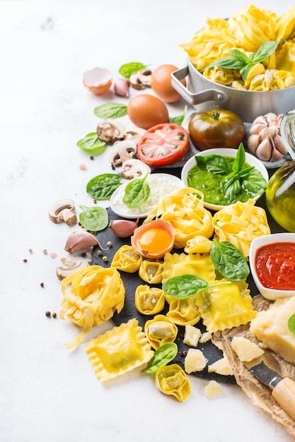 Auswahl an italienischen Speisen und Zutaten Ravioli mit Ricotta und Spinat Pasta Tortellini Pesto Tomatensauce Olivenöl Parmesan Kopieren Sie den Hintergrund