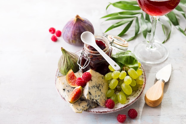 Auswahl an Käse, Beeren und Trauben mit Rotwein in Gläsern. auf Stein