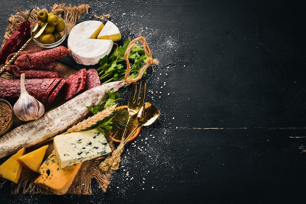 Auswahl an Käse und traditionellen Wurstwaren auf Holzhintergrund Brie-Käse Blauschimmelkäse Gorgonzola Fuete Salami Freier Platz für Text Ansicht von oben
