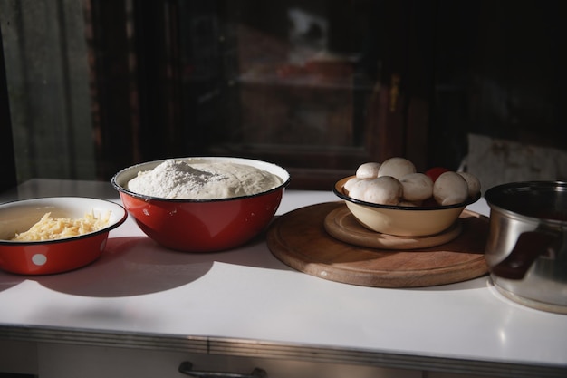 Auswahl an Kochzutaten zum Backen von Pizza in Emailleschalen auf dem Tisch in der rustikalen Küche Essen Stillleben Nahaufnahme