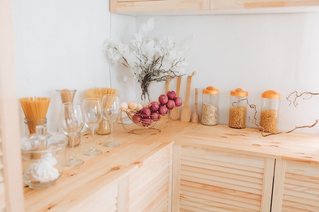 Auswahl an Müsli und Nudeln in Gläsern und Küchenutensilien auf einem Holztisch Küche im skandinavischen Stil getrockneter Knoblauch