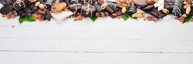 Auswahl an Schokolade mit Nüssen, Keksen und Kakao Auf einem weißen Hintergrund aus Holz Draufsicht Kopieren Sie Platz für Text