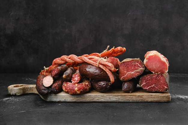 Auswahl an Schweinefleischsand-Rindfleisch-Ausages, Schinken und Fleisch auf Holzschneidebrett