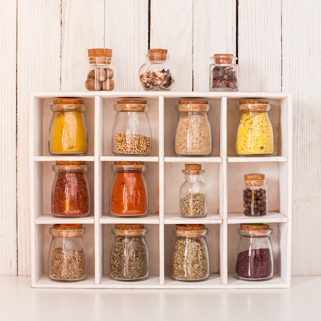 Auswahl an trockenen Gewürzen in Vintage-Glasflaschen in Holzkiste