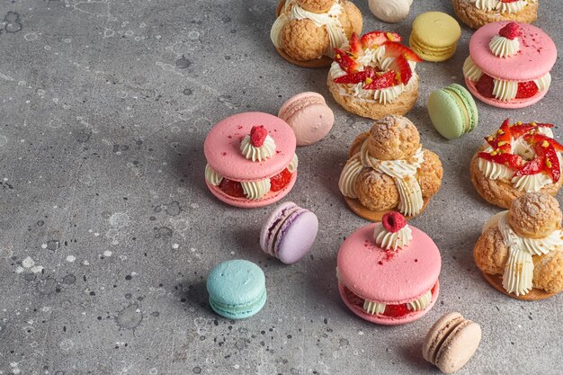 Auswahl an verschiedenen Kuchenstücken Brandgebäck Macarons Schokoladensamtkuchen auf grauem Steinhintergrund