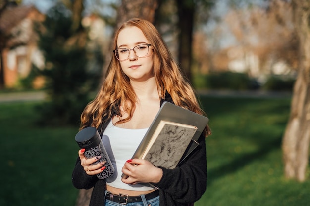 Auswahl eines weiblichen College-Studentin der Universität mit Büchern und Laptop im Freien Redhead College