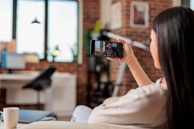 Auténtica mujer asiática ocupada en videollamada reunión comunicación en línea trabajando desde casa hablando aplicación móvil saludando hola tecnología de internet feliz llamada negocio independiente hablar