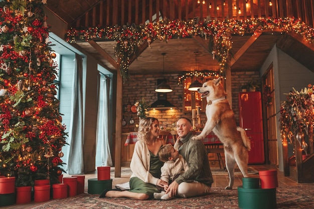 Auténtica y sincera familia feliz durante el invierno juntos disfrutando de las vacaciones con el perro en Navidad