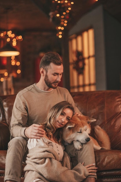 Auténtica y sincera pareja casada feliz pasa tiempo junto con un perro japonés en el albergue de Navidad