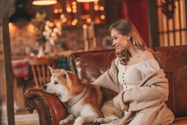 Auténtica y sincera pareja casada feliz pasa tiempo junto con un perro japonés en el albergue de Navidad