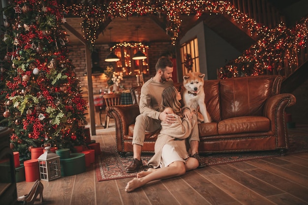 Auténtica y sincera pareja casada feliz pasa tiempo junto con un perro japonés en el albergue de Navidad