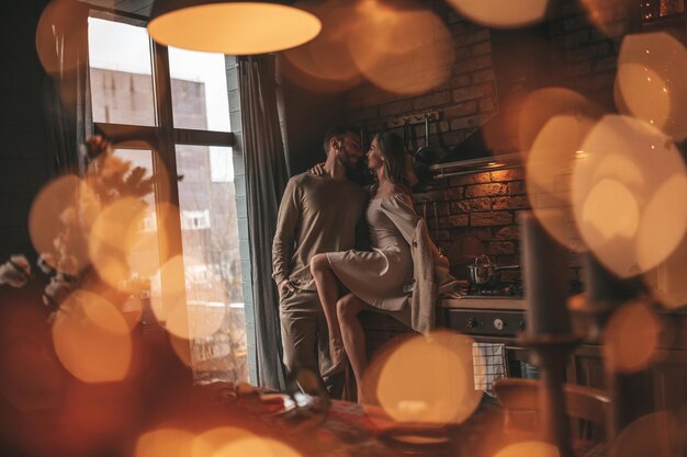 Auténtica y sincera pareja casada feliz pasando tiempo juntos en un albergue de madera decorado con Navidad