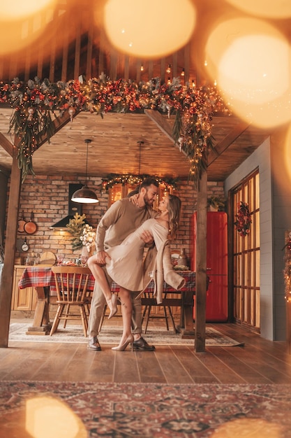 Auténtica y sincera pareja casada feliz pasando tiempo juntos en un albergue de madera decorado con Navidad