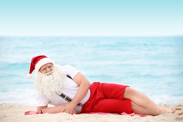 Authentischer Weihnachtsmann, der am Strand liegt