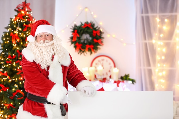 Authentischer Weihnachtsmann mit Poster im weihnachtlich dekorierten Raum