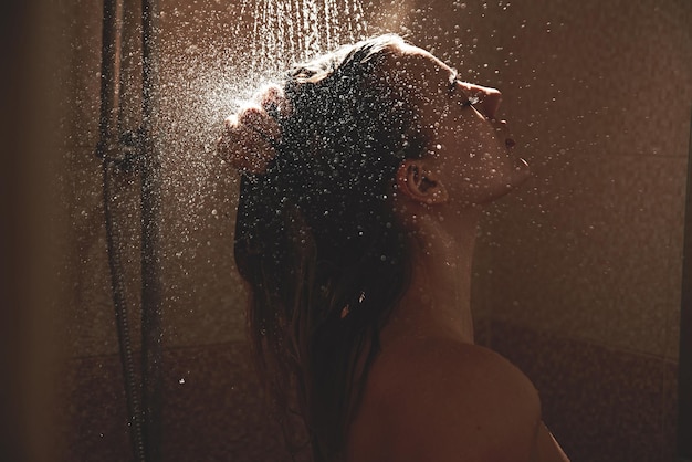 Authentisches nacktes blondes Mädchen duscht, wäscht sexy Körper mit Wassertropfen im Badezimmer, genießt es mit geschlossenen Augen