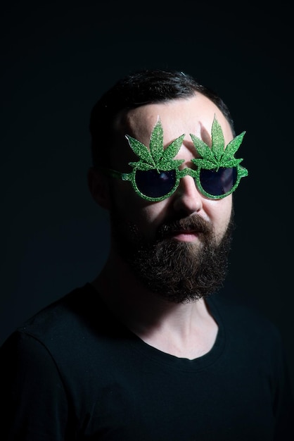 Authentisches Porträt eines fröhlichen Mannes mit Sonnenbrille Marihuana auf dunklem Hintergrund