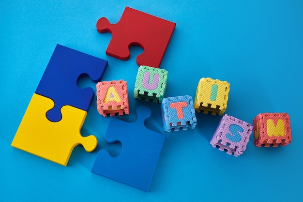 Autismo de palabras en cubos de rompecabezas sobre conciencia de autismo de fondo azul