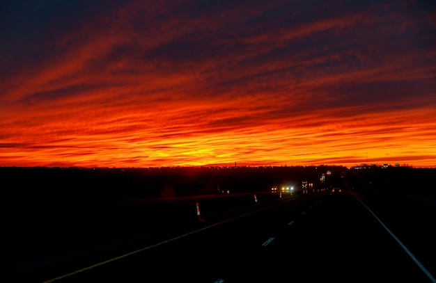 Auto auf der Straße früh im Sonnenuntergang mit Sonnenaufgang.