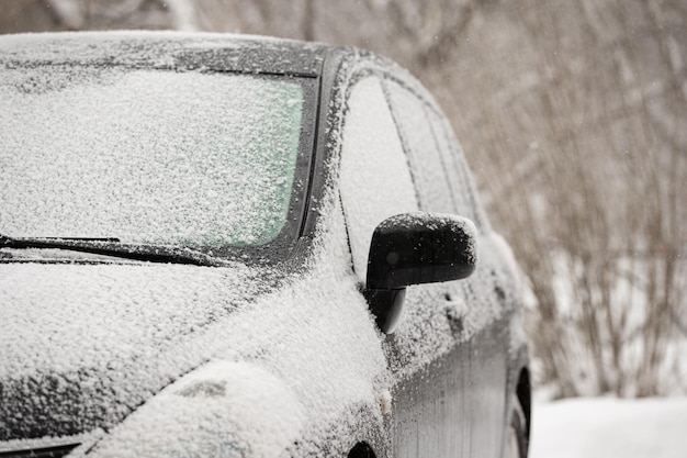 El auto en el estacionamiento está cubierto de nieve.