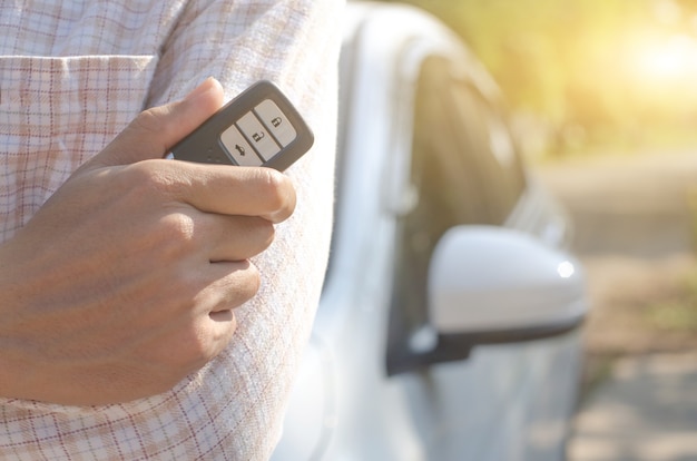 Auto-Fernbedienung mit Smart-Key, Hand mit Smart-Key zum Verriegeln der Türen des weißen Autos