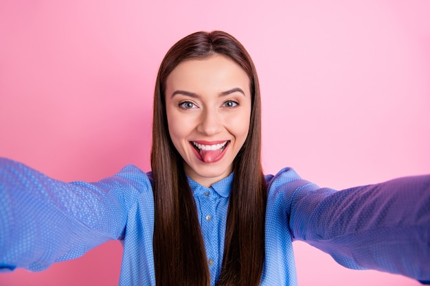 Auto-foto de mulher alegre tirando selfie mostrando a língua