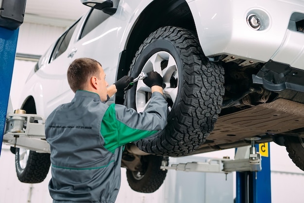 Foto auto im autoservice zur reparatur angehoben, arbeiter repariert das rad,