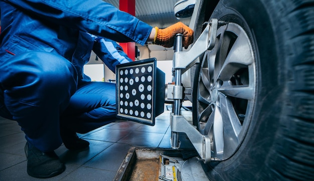 Foto auto mecânico instalando o sensor durante o ajuste da suspensão e o trabalho de alinhamento das rodas do automóvel