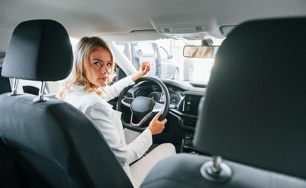 En el auto La mujer con ropa formal está adentro en el salón del automóvil