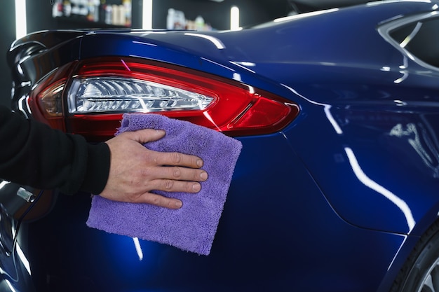 Foto auto polieren. blauer lappen in den händen. auto detaillierung in der garage.