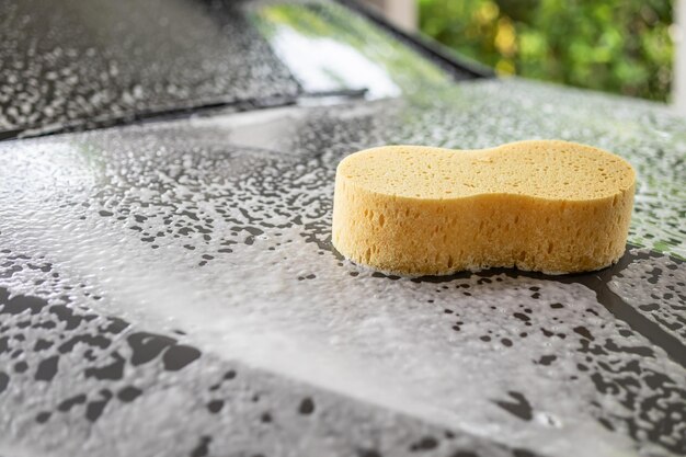 Foto auto reinigen und waschen mit gelbem schwamm und schaumseife