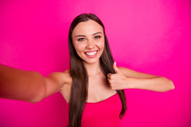 Auto-retrato dela ela bonita atraente adorável lindo conteúdo alegre alegre menina de cabelos compridos mostrando anúncio thumbup anúncio isolado em fundo brilhante vívido brilhante cor rosa fúcsia vibrante