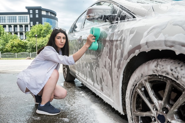 Auto sauber Mädchen mit Schwamm und Schaum waschen ihr Auto