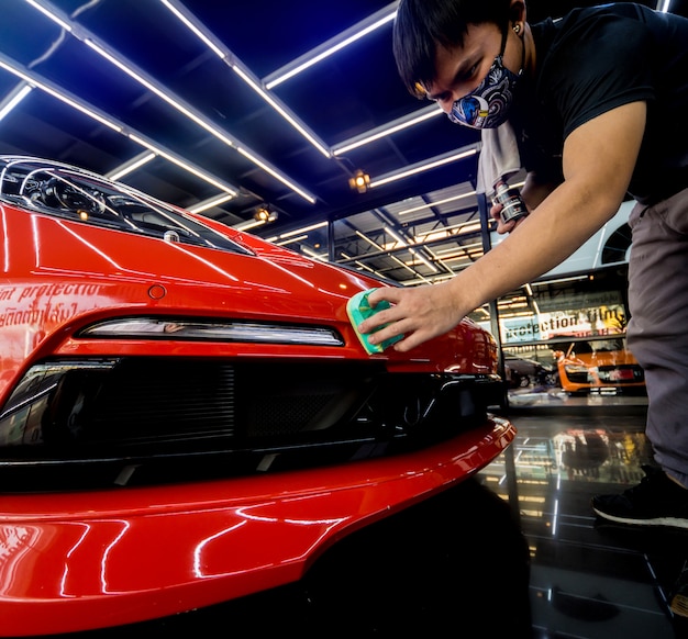 Auto-Service-Arbeiter, der eine Nano-Beschichtung auf ein Auto aufträgt