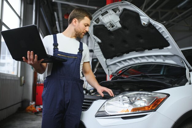 Auto-Service-Reparatur-Wartungskonzept-Mechaniker überprüft die Diagnose der Autoherstellung mit Laptop an der Tankstelle Service-Wartung von der Industrie bis zur Motorreparatur