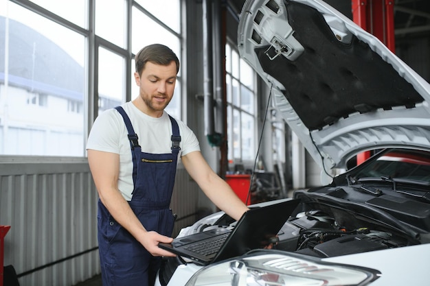 Auto-Service-Reparatur-Wartungskonzept-Mechaniker überprüft die Diagnose der Autoherstellung mit Laptop an der Tankstelle Service-Wartung von der Industrie bis zur Motorreparatur