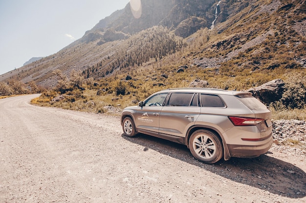 Un auto skoda para recorridos activos parado en la carretera entre el paisaje pacífico de las montañas rocosas con muchos árboles verdes. Ir de viaje en automóvil. Rusia, Altai 01, junio de 2021