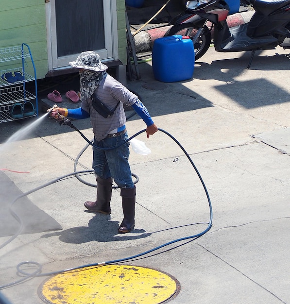 Auto waschen von Arbeitern, die mit saubererem Wasserstrahl und tagsüber im Freien stehen.