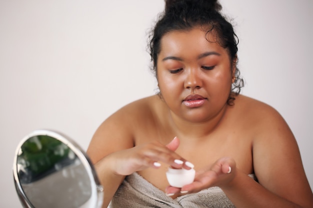 Autoajuda. Linda mulher afro-americana com roupão de banho pronta para aplicar maquiagem,