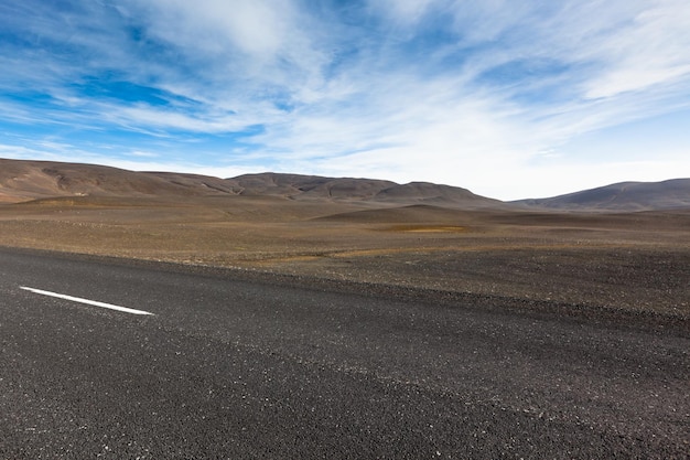 Autobahn durch Lavafeldlandschaft aus trockenem Kies unter blauem Sommerhimmel
