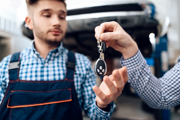 Autobesitzer gibt Schlüssel für den Automechaniker in der Garage.