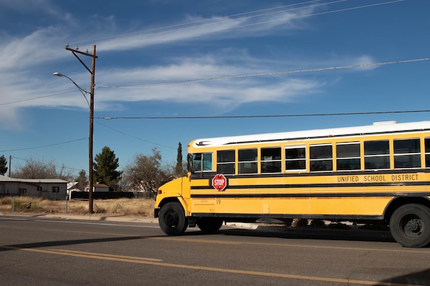 El autobús escolar se detuvo en la parada de autobús para recoger a los niños bajo el cielo azul