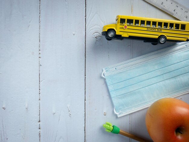 El autobús escolar y la máscara en la mesa de madera para la educación o el concepto médico