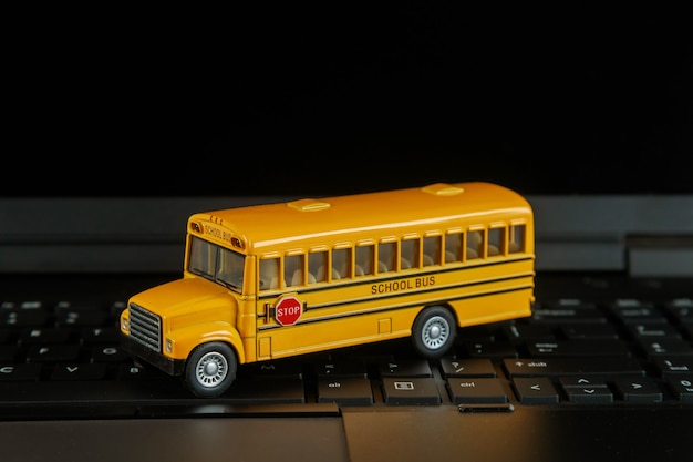 Autobús escolar en teclado de computadora de cerca con lección en línea de regreso a la escuela