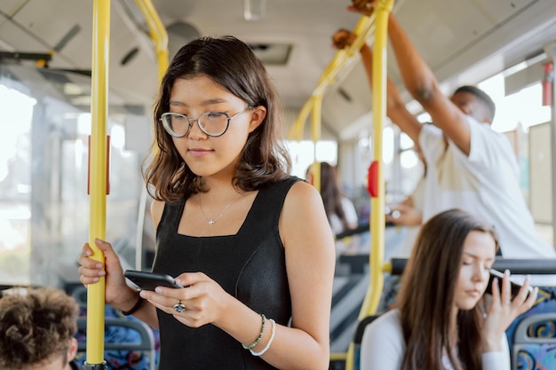 Foto autobús de transporte público abarrotado que regresa del trabajo jóvenes en mujeres universitarias con gafas