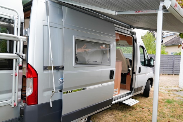 Autocaravana rv cinza estacionada porta aberta com toldo